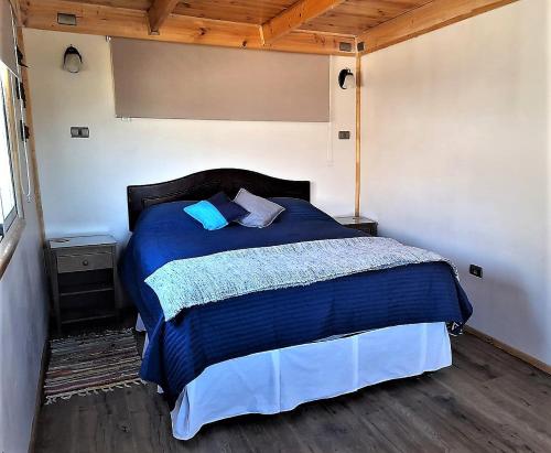 a bedroom with a bed with a blue comforter at 100 Experiencias Chile, habitación 3 in Lagunillas