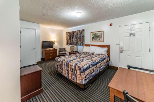 a hotel room with a bed and a table at Studio 6 Greensboro NC I40 in Greensboro