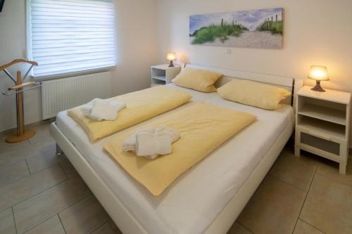 duże białe łóżko z 2 poduszkami w obiekcie Ferienwohnung-Leuchtfeuer-1-EG w mieście Norddeich