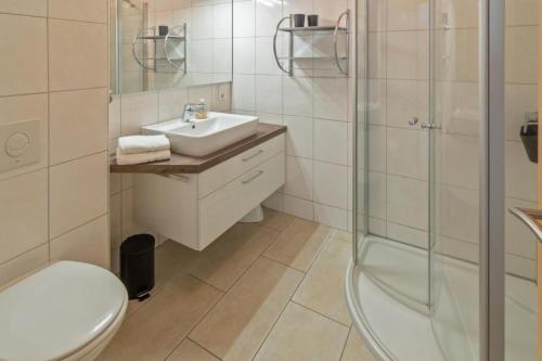 W łazience znajduje się toaleta, umywalka i prysznic. w obiekcie Ferienwohnung-Leuchtfeuer-1-EG w mieście Norddeich