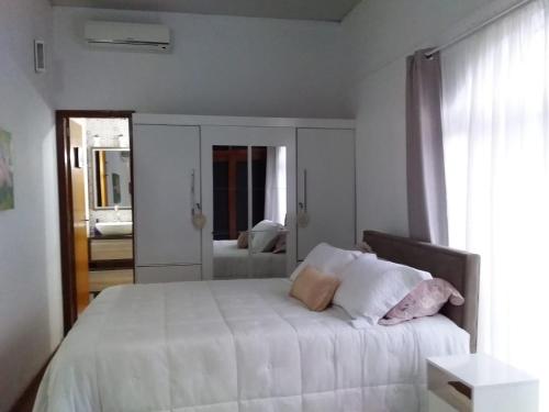 1 dormitorio con 1 cama con sábanas blancas y ventana en Residencial Viva o Verde Casa, en Florianópolis