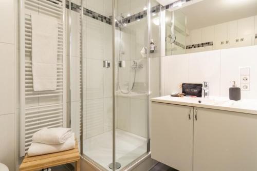 ein weißes Bad mit einer Dusche und einem Waschbecken in der Unterkunft Möwennest 8 in Großenbrode