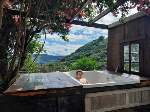 un uomo in una vasca da bagno su una terrazza di legno di Chácara paraíso dá paz a Nova Petrópolis