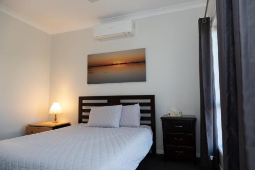 a bedroom with a bed and a lamp on a night stand at The Summer Lakeside Room in North Lakes