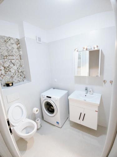 a white bathroom with a toilet and a washing machine at Apartament Ghencea Residence 158 Floor 7 in Bucharest