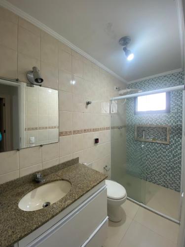 a bathroom with a sink and a toilet and a shower at Ap Guarujá, Jardim Astúrias in Guarujá