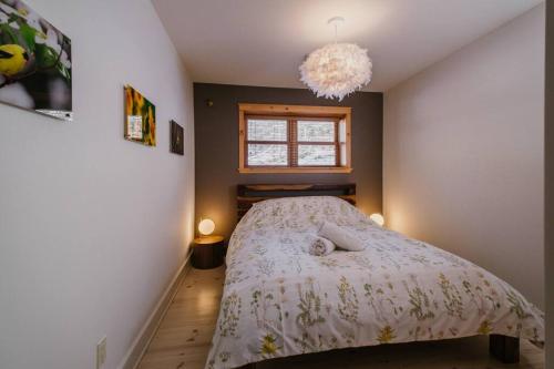 a small bedroom with a bed and a chandelier at Chalet Blue Jay Spa at Fiddler's Lake in Mille-Isles