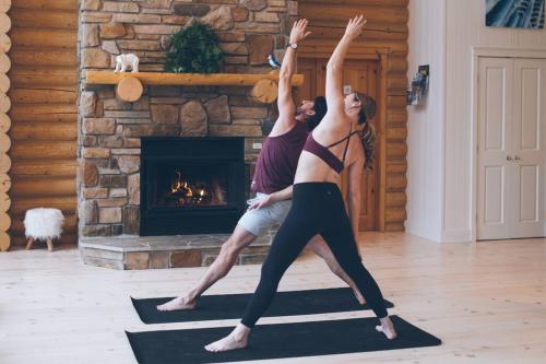 two people doing yoga in front of a fireplace at Chalet Blue Jay Spa at Fiddler's Lake in Mille-Isles