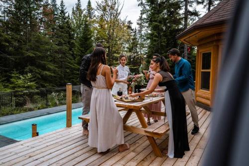 a group of people standing around a table on a deck at Chalet Blue Jay Spa at Fiddler's Lake in Mille-Isles
