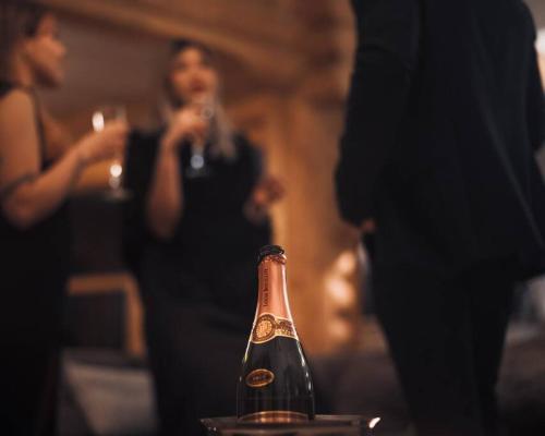 a bottle of champagne sitting on a table with people at Chalet Blue Jay Spa at Fiddler's Lake in Mille-Isles