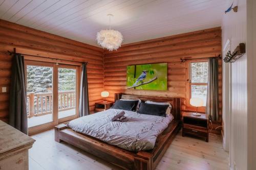 a bedroom with a bed in a room with wooden walls at Chalet Blue Jay Spa at Fiddler's Lake in Mille-Isles