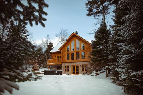 a large wooden house in the snow at Chalet Blue Jay Spa at Fiddler's Lake in Mille-Isles