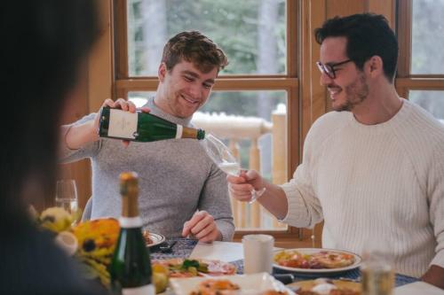 two men sitting at a table drinking wine at Chalet Blue Jay Spa at Fiddler's Lake in Mille-Isles