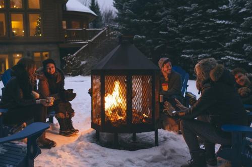a group of people sitting around a fire in the snow at Chalet Blue Jay Spa at Fiddler's Lake in Mille-Isles