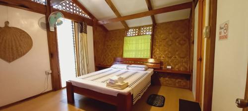 ein kleines Schlafzimmer mit einem Bett und einem Fenster in der Unterkunft Bat Tree Cottages in Agoho