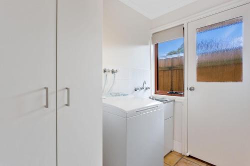uma casa de banho branca com um lavatório e uma janela em The Blue Bay em Inverloch