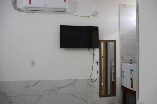 een flatscreen-tv hangend aan een muur in een badkamer bij Suítes Mar de Maragogi in Maragogi