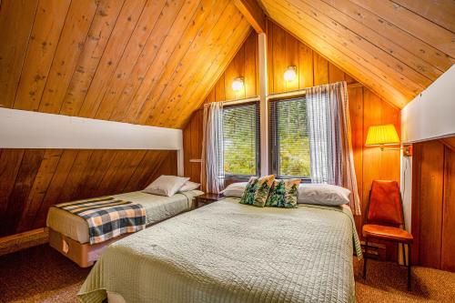 two beds in a room with wooden walls and ceilings at Peak-a-View Lakehouse in Ronald