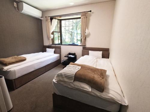 a bedroom with two beds and a window at SUIHOUEN in Numazu