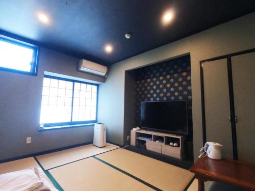 uma sala de estar com uma televisão de ecrã plano na parede em SUIHOUEN em Numazu