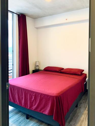 a bedroom with a large bed with red sheets at Único Apartamento en Nuevo y Moderno Condominio in San José