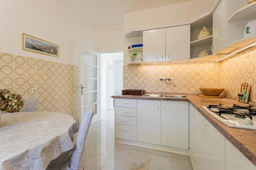 cocina con armarios blancos y encimera en Apartments by the sea Zivogosce - Porat, Makarska - 6899, en Igrane
