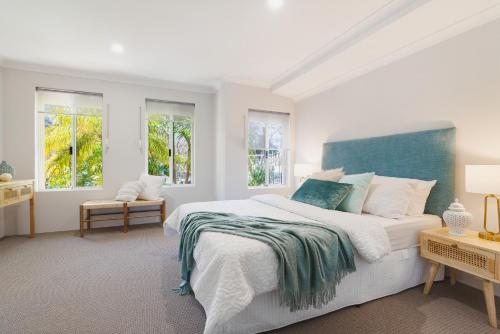 a white bedroom with a large bed and windows at Halls Head Haven in Mandurah