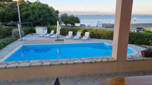 een zwembad met stoelen en de oceaan op de achtergrond bij Seaside apartments with a swimming pool Ugljan - 829 in Ugljan