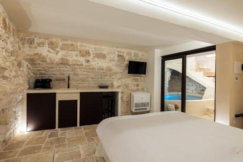 a bedroom with a white bed and a stone wall at Suite Le Grotte in Ostuni