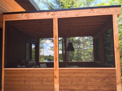 a screened in porch of a house with windows at Chalet Kabana Spa au bord du lac in Sainte-Émélie-de-lʼÉnergie