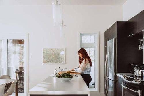 a woman is standing in a kitchen preparing food at Chalet Kabana Spa au bord du lac in Sainte-Émélie-de-lʼÉnergie
