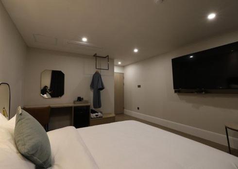 a bedroom with a large bed and a flat screen tv at H Avenue Hwamyeong in Busan