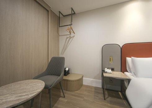 a room with a bed and a chair and a table at H Avenue Hwamyeong in Busan