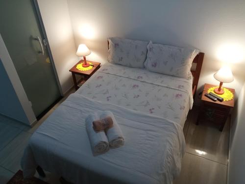 a bedroom with a bed with towels and two lamps at Chalés Vale dos Pássaros Refúgio nas montanhas in Paraty