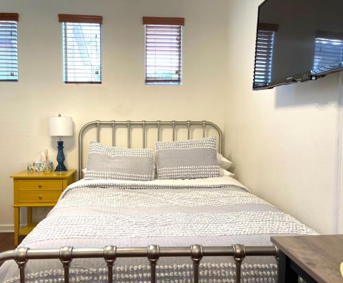 a bedroom with a bed and a table and windows at Casita Alkie in Litchfield Park