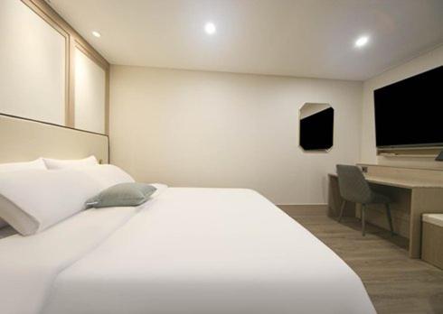 a bedroom with a large white bed and a desk at H Avenue Hwamyeong in Busan