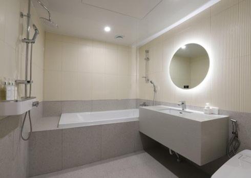 a bathroom with a tub and a sink and a mirror at H Avenue Hwamyeong in Busan