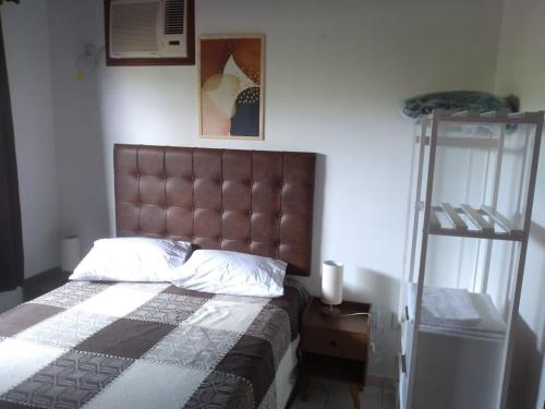 1 dormitorio con 1 cama con cabecero marrón y escalera en Casa agradável em meio a natureza., en Santa Cruz Cabrália