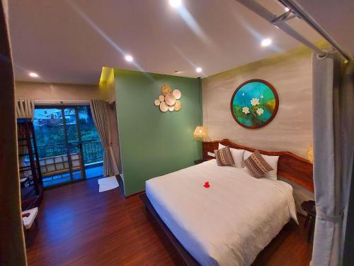 a bedroom with a white bed and a green wall at Hoi An Ti Hon House in Hoi An