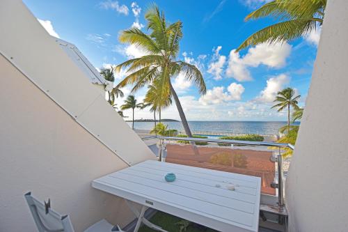 un banco blanco en un balcón con vistas a la playa en Deja Blue - Comfortable Beachfront condo, en Marigot
