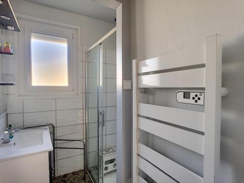 La salle de bains est pourvue d'un lavabo et d'une porte de douche en verre. dans l'établissement Maison de plain-pied avec terrasse, centre ville, à 150m de la plage - FR-1-361-334, à Jullouville