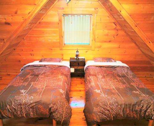 two beds in a room with a attic at 【那須高原の自然に囲まれたログハウス1棟貸し】ファミリー利用、大人数での利用、パーティも大歓迎！ in Nasu-yumoto