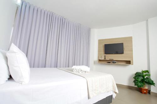a bedroom with a white bed and a tv at Apartamento 1009 in Goiânia