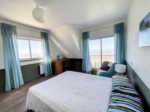 une chambre avec un lit, une chaise et des fenêtres dans l'établissement Villa avec jardin et accès direct plage, terrasse, 5 chambres, 2 salles d'eau, wifi, parking - FR-1-361-132, à Saint-Pair-sur-Mer