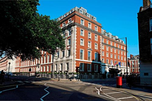 un grand bâtiment en briques rouges dans une rue de la ville dans l'établissement London Marriott Hotel Grosvenor Square, à Londres