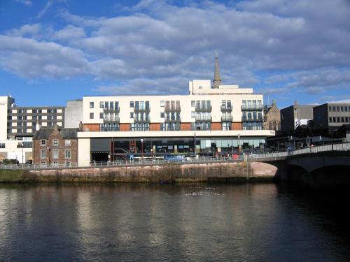 a building next to a river with a bridge at Highland Apartments by Mansley in Inverness