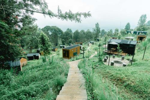 Bobocabin Gunung Mas, Puncak في Tagalbato: مجموعة منازل في حقل مع مسار خشبي