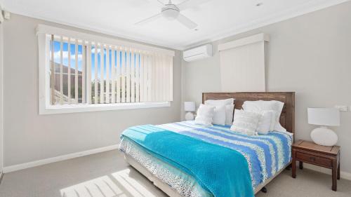 a white bedroom with a bed and a window at Bay Escape in Nelson Bay
