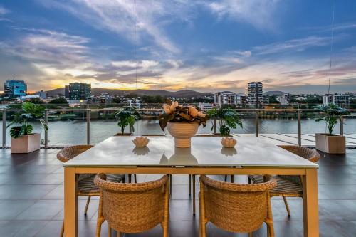 a table and chairs on a balcony with a view of a city at Stunning Waterfront Penthouse 3 or 4 Bedrooms in Brisbane