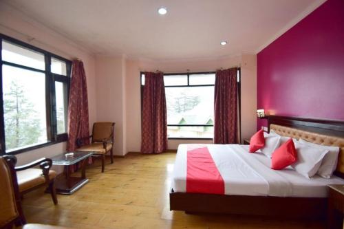 a hotel room with a bed with a red wall at Goroomgo Marc Shimla Near Mall Road - Luxury Room - Excellent Service - Ample Parking - Best Hotel in Shimla in Shimla